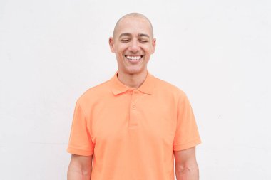 Orta yaşlı, turuncu polo tişörtlü, beyaz duvarlı yakışıklı bir İspanyol 'un stüdyo portresi. Günlük yaşam tarzı ve moda konsepti.