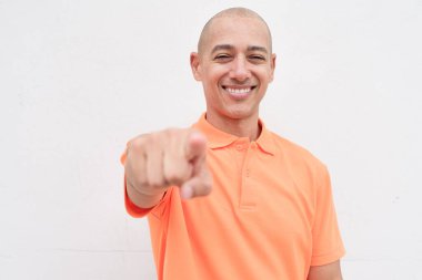 Orta yaşlı, turuncu polo tişörtlü, beyaz duvarlı yakışıklı bir İspanyol 'un stüdyo portresi. Günlük yaşam tarzı ve moda konsepti.