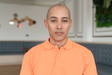 Kafe masasında oturan orta yaşlı, turuncu polo tişörtlü yakışıklı, kel bir İtalyan. Günlük yaşam tarzı kavramı.