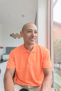 Kafe masasında oturan orta yaşlı, turuncu polo tişörtlü yakışıklı, kel bir İtalyan. Günlük yaşam tarzı kavramı.