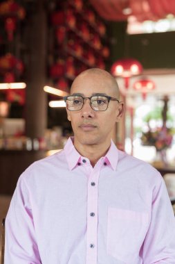 40 'lı yaşlarda kel, olgun bir erkek. Çin tarzı çay evinde pembe günlük iş gömleği ve gözlük takıyor. Kültür, rahatlama ve yaşam tarzı kavramı.