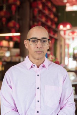 40 'lı yaşlarda kel, olgun bir erkek. Çin tarzı çay evinde pembe günlük iş gömleği ve gözlük takıyor. Kültür, rahatlama ve yaşam tarzı kavramı.