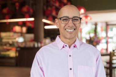 40 'lı yaşlarda kel, olgun bir erkek. Çin tarzı çay evinde pembe günlük iş gömleği ve gözlük takıyor. Kültür, rahatlama ve yaşam tarzı kavramı.