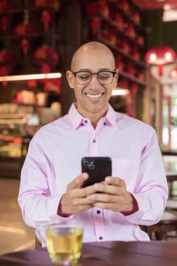 40 'lı yaşlarda kel, olgun bir erkek. Çin tarzı çay evinde pembe günlük iş gömleği ve gözlük takıyor. Kültür, rahatlama ve yaşam tarzı kavramı.