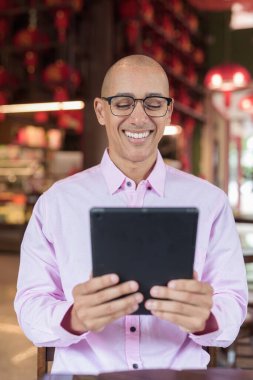 40 'lı yaşlarda kel, olgun bir erkek. Çin tarzı çay evinde pembe günlük iş gömleği ve gözlük takıyor. Kültür, rahatlama ve yaşam tarzı kavramı.