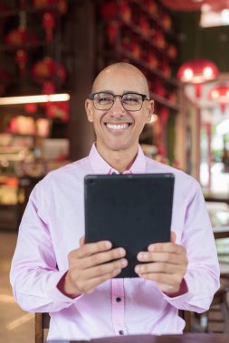 40 'lı yaşlarda kel, olgun bir erkek. Çin tarzı çay evinde pembe günlük iş gömleği ve gözlük takıyor. Kültür, rahatlama ve yaşam tarzı kavramı.