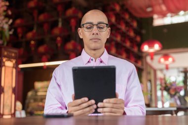 40 'lı yaşlarda kel, olgun bir erkek. Çin tarzı çay evinde pembe günlük iş gömleği ve gözlük takıyor. Kültür, rahatlama ve yaşam tarzı kavramı.