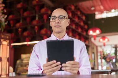 40 'lı yaşlarda kel, olgun bir erkek. Çin tarzı çay evinde pembe günlük iş gömleği ve gözlük takıyor. Kültür, rahatlama ve yaşam tarzı kavramı.