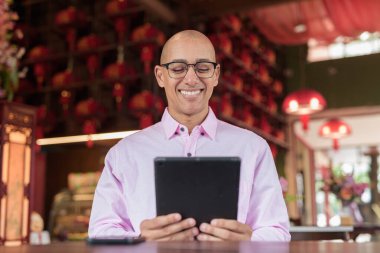 40 'lı yaşlarda kel, olgun bir erkek. Çin tarzı çay evinde pembe günlük iş gömleği ve gözlük takıyor. Kültür, rahatlama ve yaşam tarzı kavramı.