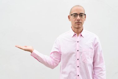 40 'lı yaşlarda, kel, olgun bir erkek. Sıradan pembe iş gömleği ve gözlük takıyor. Düz beyaz duvarın önünde duruyor. Şirket, iş ve yaşam tarzı kavramları için stüdyo tarzı görüntü kullanışlıdır.