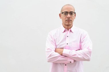 40 'lı yaşlarda, kel, olgun bir erkek. Sıradan pembe iş gömleği ve gözlük takıyor. Düz beyaz duvarın önünde duruyor. Şirket, iş ve yaşam tarzı kavramları için stüdyo tarzı görüntü kullanışlıdır.