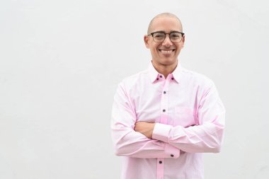 40 'lı yaşlarda, kel, olgun bir erkek. Sıradan pembe iş gömleği ve gözlük takıyor. Düz beyaz duvarın önünde duruyor. Şirket, iş ve yaşam tarzı kavramları için stüdyo tarzı görüntü kullanışlıdır.