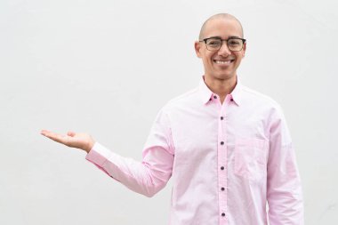 40 'lı yaşlarda, kel, olgun bir erkek. Sıradan pembe iş gömleği ve gözlük takıyor. Düz beyaz duvarın önünde duruyor. Şirket, iş ve yaşam tarzı kavramları için stüdyo tarzı görüntü kullanışlıdır.