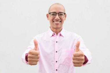 40 'lı yaşlarda, kel, olgun bir erkek. Sıradan pembe iş gömleği ve gözlük takıyor. Düz beyaz duvarın önünde duruyor. Şirket, iş ve yaşam tarzı kavramları için stüdyo tarzı görüntü kullanışlıdır.