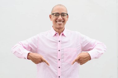 40 'lı yaşlarda, kel, olgun bir erkek. Sıradan pembe iş gömleği ve gözlük takıyor. Düz beyaz duvarın önünde duruyor. Şirket, iş ve yaşam tarzı kavramları için stüdyo tarzı görüntü kullanışlıdır.