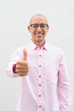 40 'lı yaşlarda, kel, olgun bir erkek. Sıradan pembe iş gömleği ve gözlük takıyor. Düz beyaz duvarın önünde duruyor. Şirket, iş ve yaşam tarzı kavramları için stüdyo tarzı görüntü kullanışlıdır.