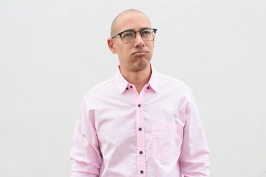 40 'lı yaşlarda, kel, olgun bir erkek. Sıradan pembe iş gömleği ve gözlük takıyor. Düz beyaz duvarın önünde duruyor. Şirket, iş ve yaşam tarzı kavramları için stüdyo tarzı görüntü kullanışlıdır.