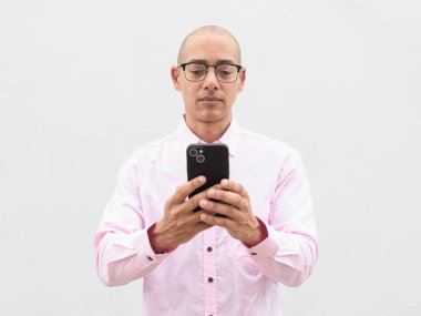 40 'lı yaşlarda, kel, olgun bir erkek. Sıradan pembe iş gömleği ve gözlük takıyor. Düz beyaz duvarın önünde duruyor. Şirket, iş ve yaşam tarzı kavramları için stüdyo tarzı görüntü kullanışlıdır.