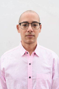 40 'lı yaşlarda, kel, olgun bir erkek. Sıradan pembe iş gömleği ve gözlük takıyor. Düz beyaz duvarın önünde duruyor. Şirket, iş ve yaşam tarzı kavramları için stüdyo tarzı görüntü kullanışlıdır.