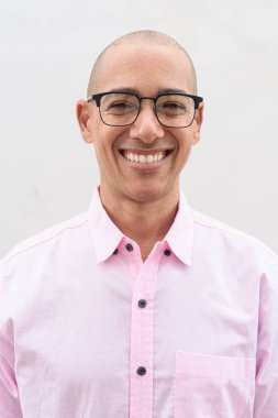 40 'lı yaşlarda, kel, olgun bir erkek. Sıradan pembe iş gömleği ve gözlük takıyor. Düz beyaz duvarın önünde duruyor. Şirket, iş ve yaşam tarzı kavramları için stüdyo tarzı görüntü kullanışlıdır.