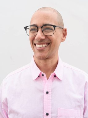 40 'lı yaşlarda, kel, olgun bir erkek. Sıradan pembe iş gömleği ve gözlük takıyor. Düz beyaz duvarın önünde duruyor. Şirket, iş ve yaşam tarzı kavramları için stüdyo tarzı görüntü kullanışlıdır.