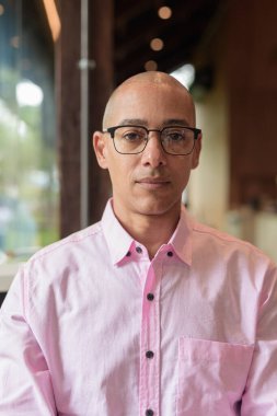 40 'lı yaşlarda kel, yetişkin bir erkek modern kahve dükkanında pembe günlük iş gömleği ve gözlük takıyor şehir yaşam tarzı, eğlence, kafe kültürü ve sosyal rahatlama kavramı..