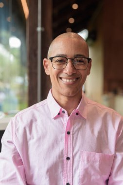 40 'lı yaşlarda kel, yetişkin bir erkek modern kahve dükkanında pembe günlük iş gömleği ve gözlük takıyor şehir yaşam tarzı, eğlence, kafe kültürü ve sosyal rahatlama kavramı..