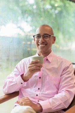 40 'lı yaşlarda kel, yetişkin bir erkek modern kahve dükkanında pembe günlük iş gömleği ve gözlük takıyor şehir yaşam tarzı, eğlence, kafe kültürü ve sosyal rahatlama kavramı..