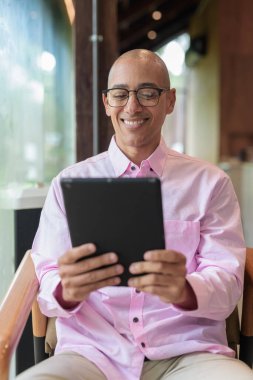 40 'lı yaşlarda kel, yetişkin bir erkek modern kahve dükkanında pembe günlük iş gömleği ve gözlük takıyor şehir yaşam tarzı, eğlence, kafe kültürü ve sosyal rahatlama kavramı..