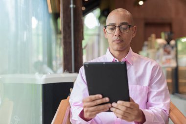 40 'lı yaşlarda kel, yetişkin bir erkek modern kahve dükkanında pembe günlük iş gömleği ve gözlük takıyor şehir yaşam tarzı, eğlence, kafe kültürü ve sosyal rahatlama kavramı..