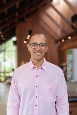 40 'lı yaşlarda kel, yetişkin bir erkek modern kahve dükkanında pembe günlük iş gömleği ve gözlük takıyor şehir yaşam tarzı, eğlence, kafe kültürü ve sosyal rahatlama kavramı..