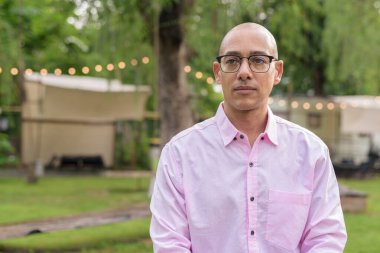 40 'lı yaşlarda kel, olgun bir erkek pembe gömlek ve gözlük takıyor. Kamp alanı çevresi ve karavan geçmişi var. Açık hava eğlence ortamında seyahat, turizm ve yaşam tarzı kavramı.