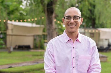 40 'lı yaşlarda kel, olgun bir erkek pembe gömlek ve gözlük takıyor. Kamp alanı çevresi ve karavan geçmişi var. Açık hava eğlence ortamında seyahat, turizm ve yaşam tarzı kavramı.