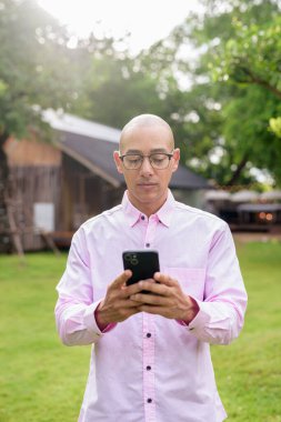 40 'lı yaşlarda kel, olgun bir erkek pembe gömlek ve gözlük takıyor. Kamp alanı çevresi ve karavan geçmişi var. Açık hava eğlence ortamında seyahat, turizm ve yaşam tarzı kavramı.