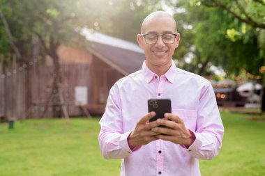 40 'lı yaşlarda kel, olgun bir erkek pembe gömlek ve gözlük takıyor. Kamp alanı çevresi ve karavan geçmişi var. Açık hava eğlence ortamında seyahat, turizm ve yaşam tarzı kavramı.