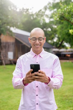 40 'lı yaşlarda kel, olgun bir erkek pembe gömlek ve gözlük takıyor. Kamp alanı çevresi ve karavan geçmişi var. Açık hava eğlence ortamında seyahat, turizm ve yaşam tarzı kavramı.