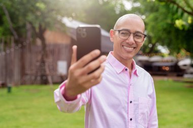 40 'lı yaşlarda kel, olgun bir erkek pembe gömlek ve gözlük takıyor. Kamp alanı çevresi ve karavan geçmişi var. Açık hava eğlence ortamında seyahat, turizm ve yaşam tarzı kavramı.