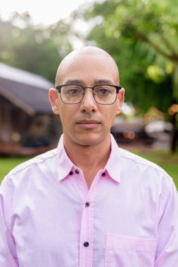 40 'lı yaşlarda kel, olgun bir erkek pembe gömlek ve gözlük takıyor. Kamp alanı çevresi ve karavan geçmişi var. Açık hava eğlence ortamında seyahat, turizm ve yaşam tarzı kavramı.