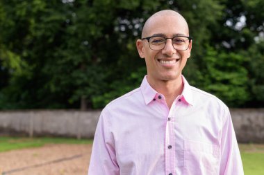 40 'lı yaşlarda kel, olgun bir erkek pembe gömlek ve gözlük takıyor. Kamp alanı çevresi ve karavan geçmişi var. Açık hava eğlence ortamında seyahat, turizm ve yaşam tarzı kavramı.