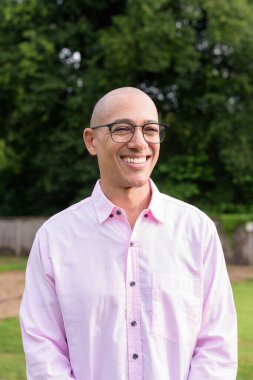 40 'lı yaşlarda kel, olgun bir erkek pembe gömlek ve gözlük takıyor. Kamp alanı çevresi ve karavan geçmişi var. Açık hava eğlence ortamında seyahat, turizm ve yaşam tarzı kavramı.