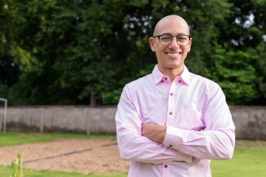 40 'lı yaşlarda kel, olgun bir erkek pembe gömlek ve gözlük takıyor. Kamp alanı çevresi ve karavan geçmişi var. Açık hava eğlence ortamında seyahat, turizm ve yaşam tarzı kavramı.