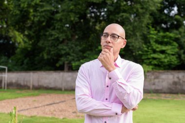 40 'lı yaşlarda kel, olgun bir erkek pembe gömlek ve gözlük takıyor. Kamp alanı çevresi ve karavan geçmişi var. Açık hava eğlence ortamında seyahat, turizm ve yaşam tarzı kavramı.