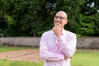 40 'lı yaşlarda kel, olgun bir erkek pembe gömlek ve gözlük takıyor. Kamp alanı çevresi ve karavan geçmişi var. Açık hava eğlence ortamında seyahat, turizm ve yaşam tarzı kavramı.