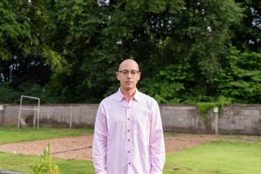 40 'lı yaşlarda kel, olgun bir erkek pembe gömlek ve gözlük takıyor. Kamp alanı çevresi ve karavan geçmişi var. Açık hava eğlence ortamında seyahat, turizm ve yaşam tarzı kavramı.