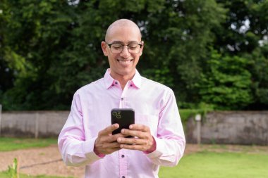 40 'lı yaşlarda kel, olgun bir erkek pembe gömlek ve gözlük takıyor. Kamp alanı çevresi ve karavan geçmişi var. Açık hava eğlence ortamında seyahat, turizm ve yaşam tarzı kavramı.