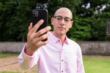 40 'lı yaşlarda kel, olgun bir erkek pembe gömlek ve gözlük takıyor. Kamp alanı çevresi ve karavan geçmişi var. Açık hava eğlence ortamında seyahat, turizm ve yaşam tarzı kavramı.