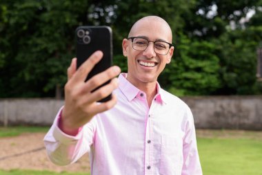 40 'lı yaşlarda kel, olgun bir erkek pembe gömlek ve gözlük takıyor. Kamp alanı çevresi ve karavan geçmişi var. Açık hava eğlence ortamında seyahat, turizm ve yaşam tarzı kavramı.