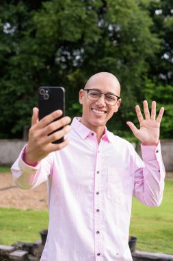 40 'lı yaşlarda kel, olgun bir erkek pembe gömlek ve gözlük takıyor. Kamp alanı çevresi ve karavan geçmişi var. Açık hava eğlence ortamında seyahat, turizm ve yaşam tarzı kavramı.