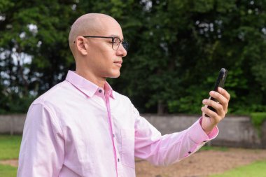 40 'lı yaşlarda kel, olgun bir erkek pembe gömlek ve gözlük takıyor. Kamp alanı çevresi ve karavan geçmişi var. Açık hava eğlence ortamında seyahat, turizm ve yaşam tarzı kavramı.