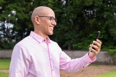 40 'lı yaşlarda kel, olgun bir erkek pembe gömlek ve gözlük takıyor. Kamp alanı çevresi ve karavan geçmişi var. Açık hava eğlence ortamında seyahat, turizm ve yaşam tarzı kavramı.